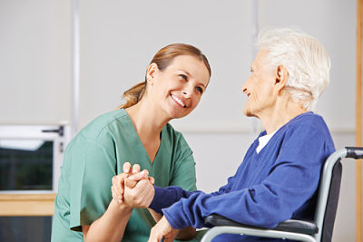 Picture of a female nurse is holding the hand of a female elderly patient.